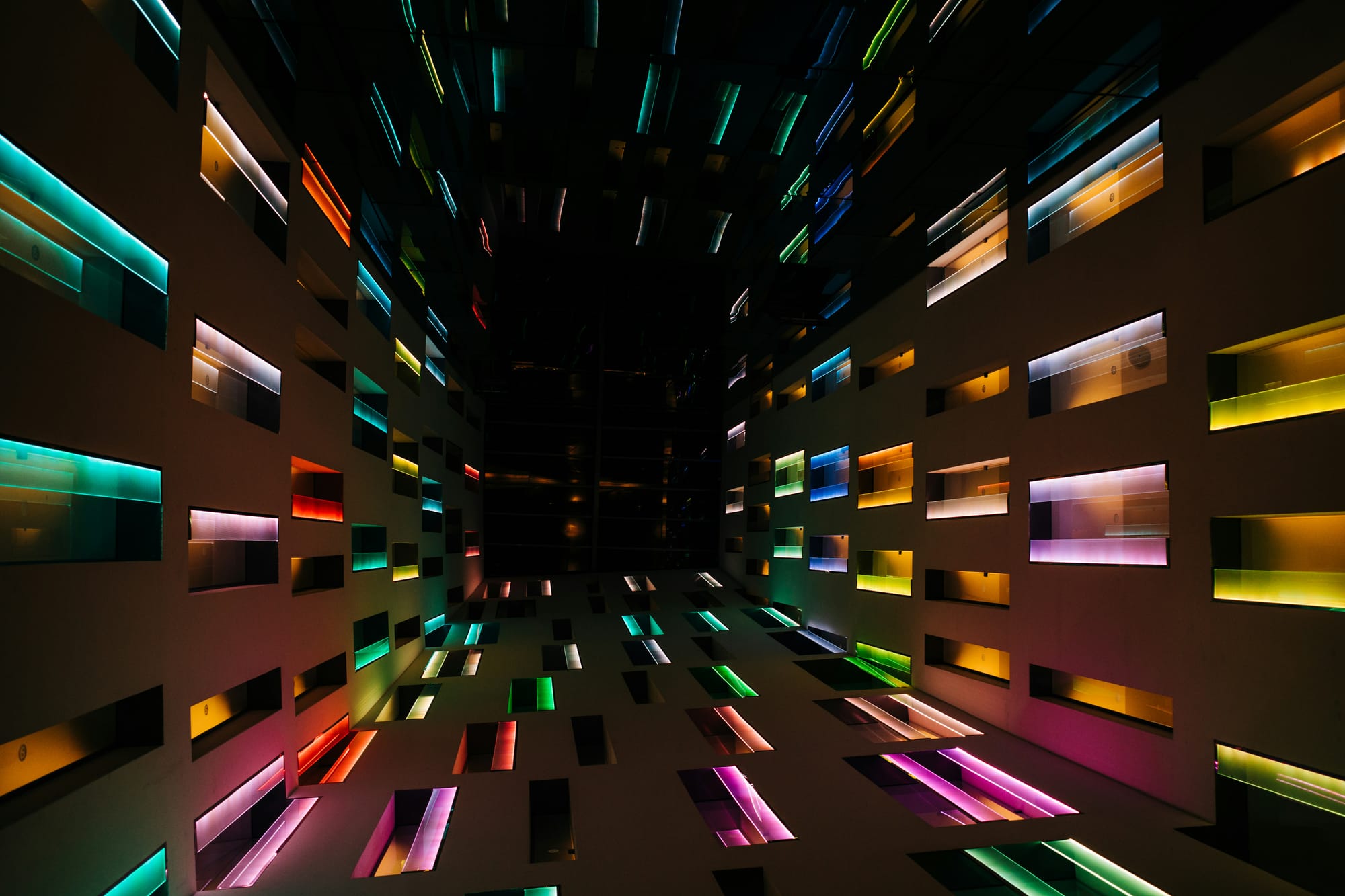 An immersive art installation with colourful glowing light panels in a dark space