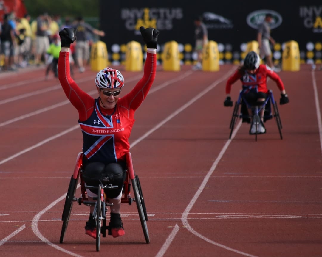 A person in a wheelchair on a dimly lit stage, illuminated by a single spotlight, suggesting a powerful performance.