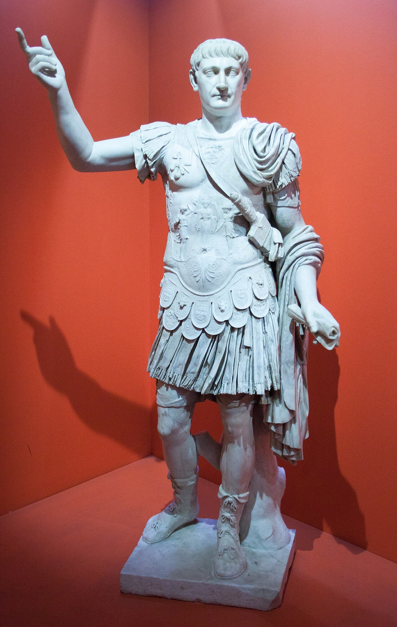 A full-length ancient Roman marble statue of Emperor Trajan in military attire, with detailed carvings on his breastplate and cloak.