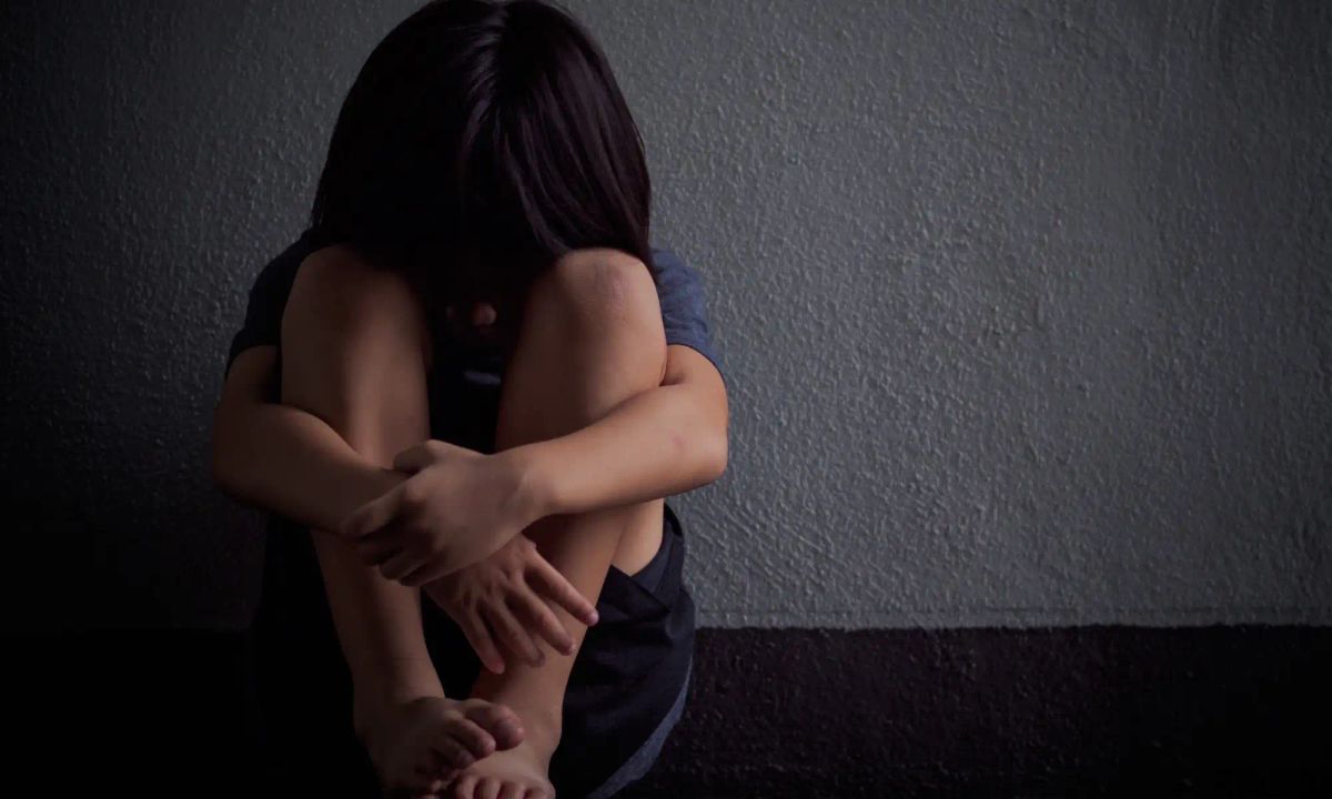 Ängstliches, unsicheres, einsames, trauriges Kind in isolierender, schützender Körperhaltung mit angezogenen Beinen