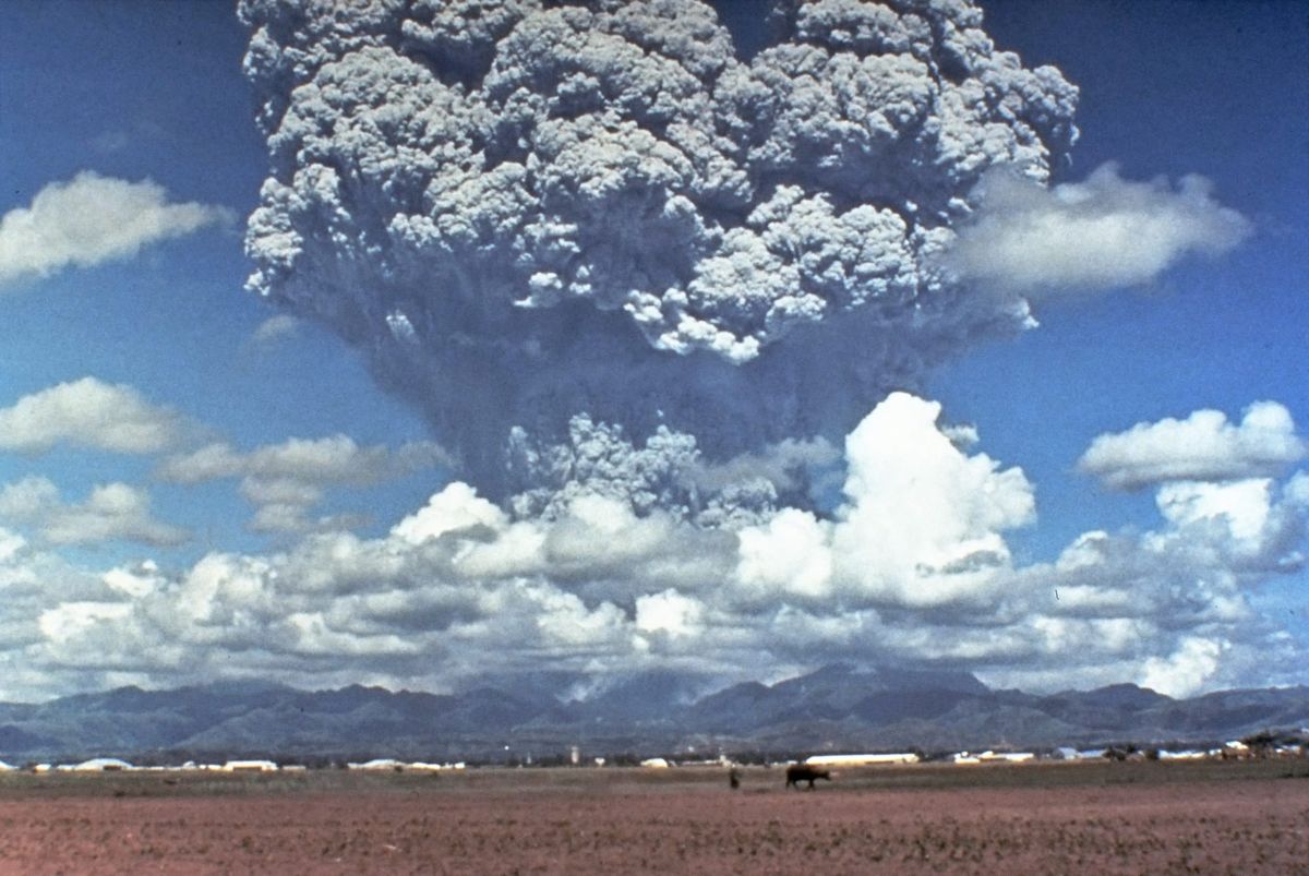 Photograph showing a cloud of gray volcanic ash above a range of mountains.