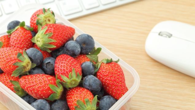A healthy snack while you work Image of a punnet of strawberries and blueberries next to a computer mouse and keyboard