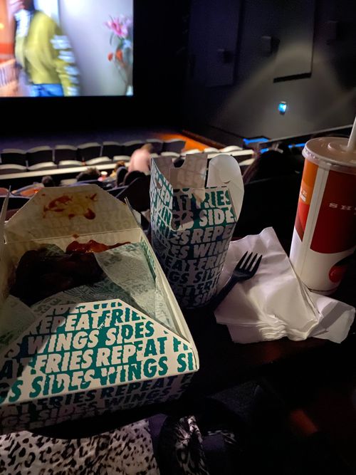 Boxes of food from Wingstop on a table overlooking a cinema screen