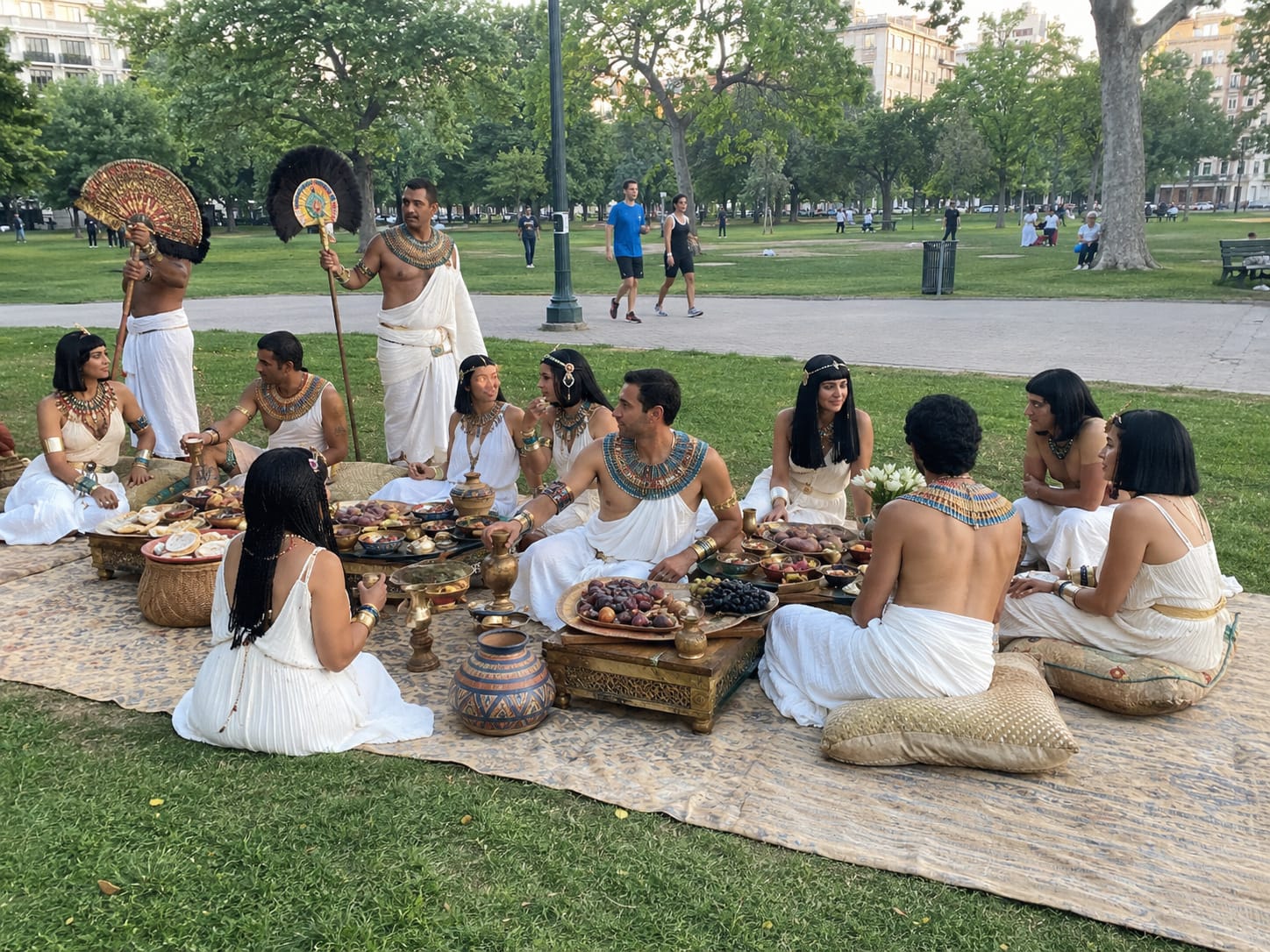 Ancient Egyptian diners in white linen and jeweled collars feast at low tables while attendants hold feather fans.