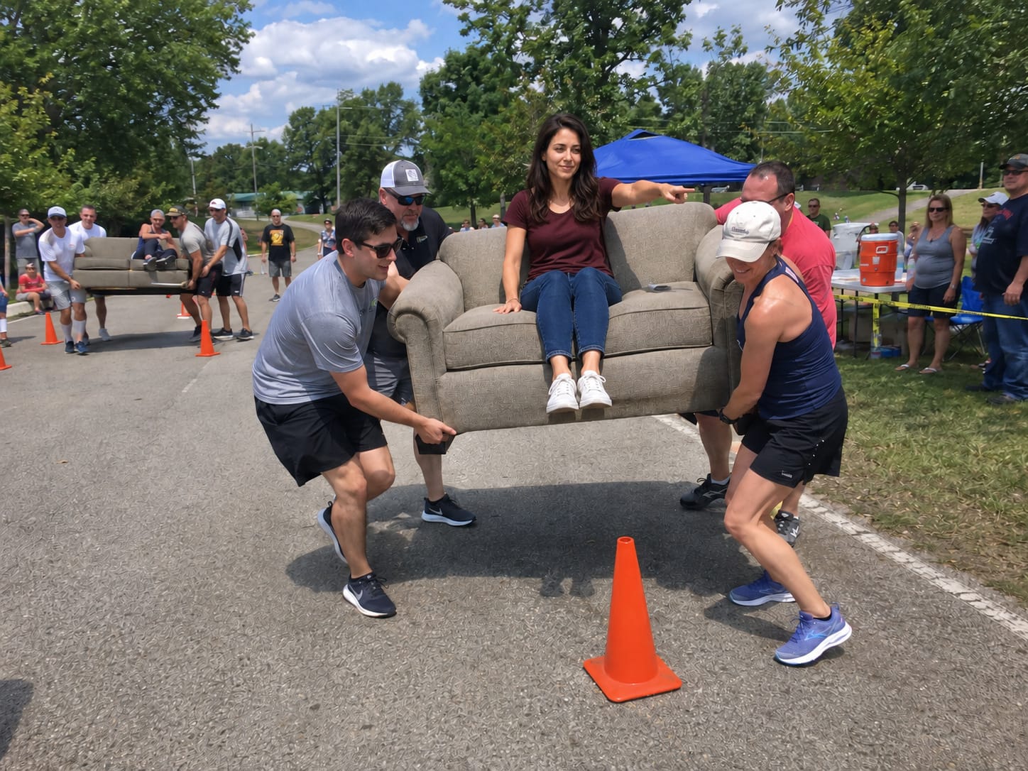 A team carries a full-size sofa around cones while one teammate stays seated on it and points directions.
