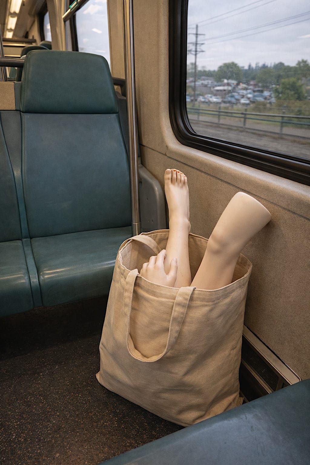 Mannequin arm and leg protruding from a large shopping bag on a commuter train.