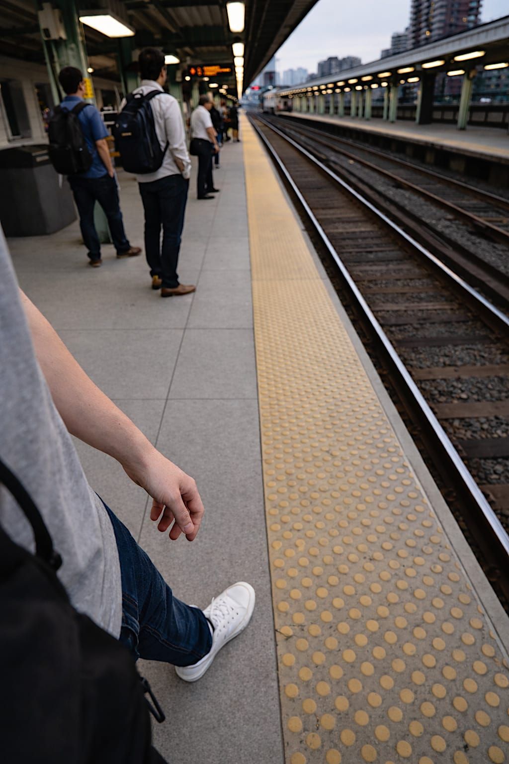 Person waiting on a commuter train platform after work in a partial selfie.