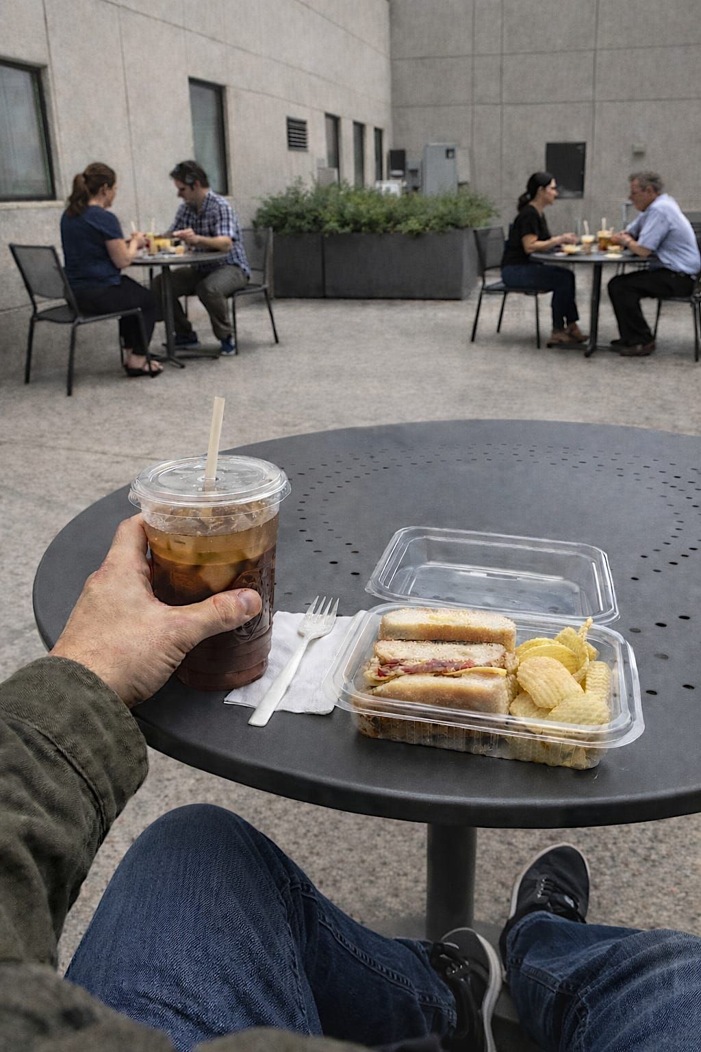 Takeout lunch and drink on an outdoor courtyard table near an office.