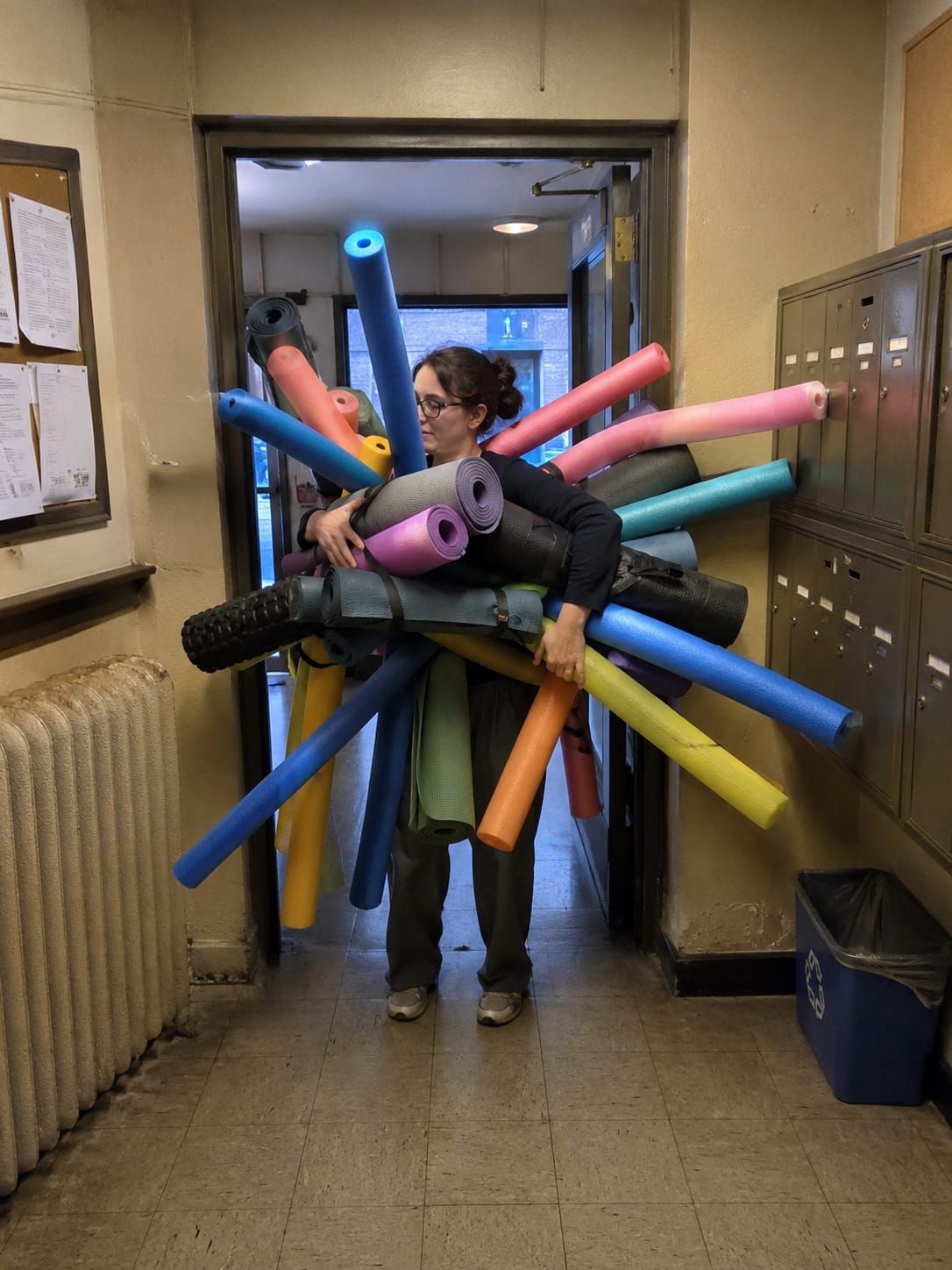 Neighbor in apartment lobby carries pool noodles and yoga mats radiating outward, blocking the entrance like a soft sea creature.