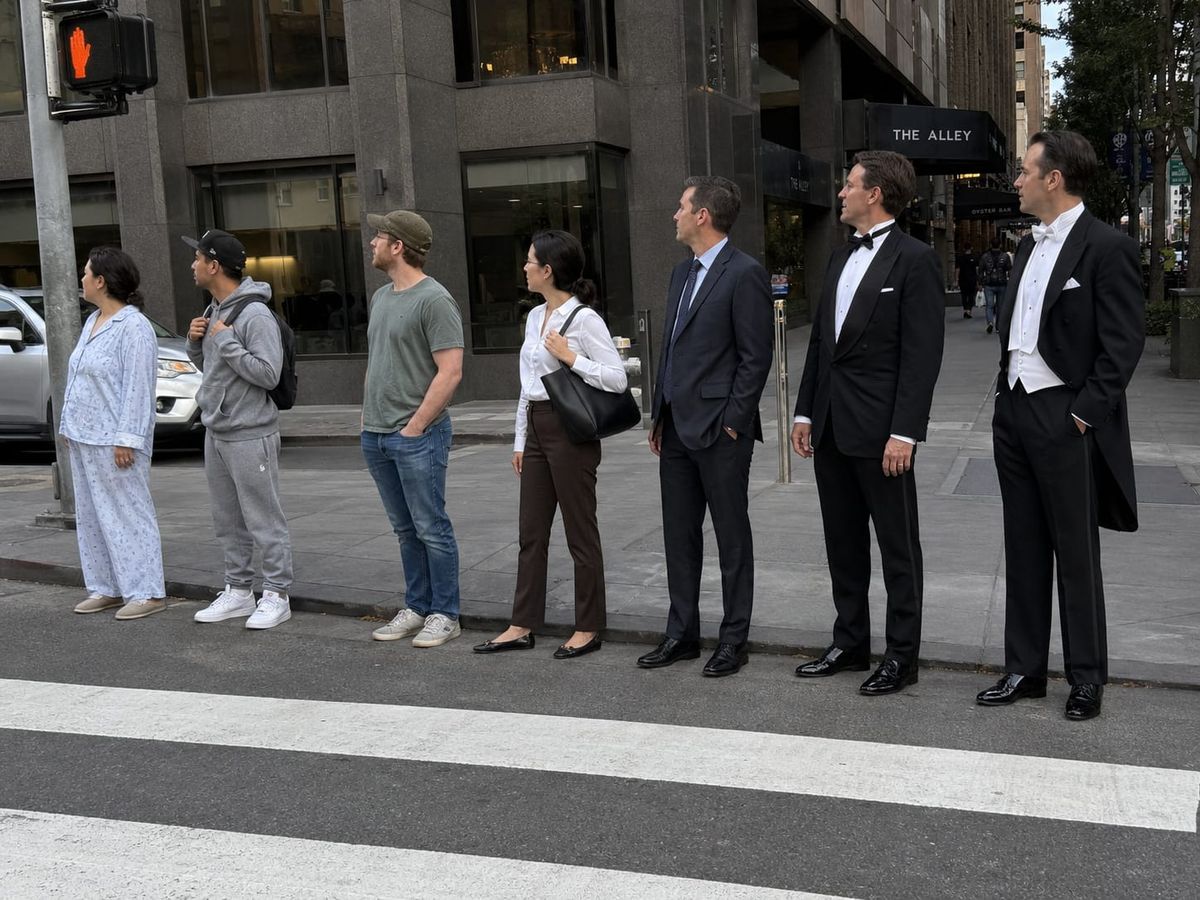 Seven people wait at a crosswalk, their clothes progressing from pajamas to sweatpants, casual wear, suits, tuxedo, and white tie.