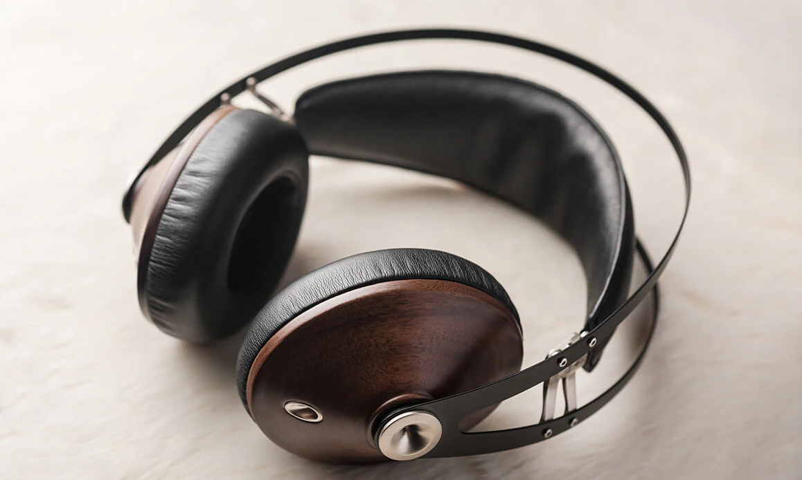 A pair of headphones with leather padding and with ear cups made of polished walnut. They are at once beautiful and insufferable.