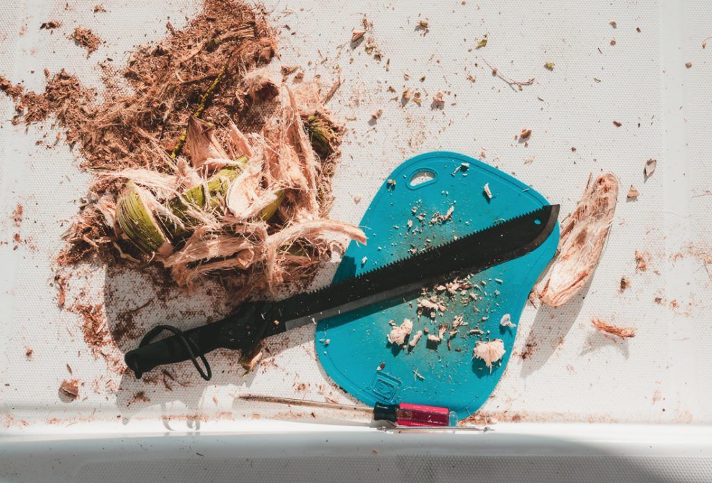 using machete to hack into coconuts on a sailboat