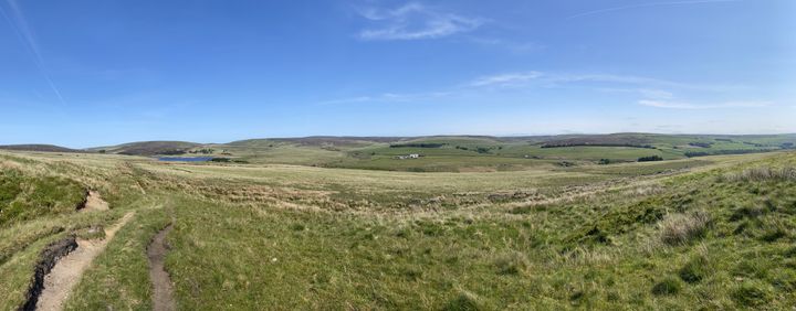Wide view across open moorland beneath a blue sky.
