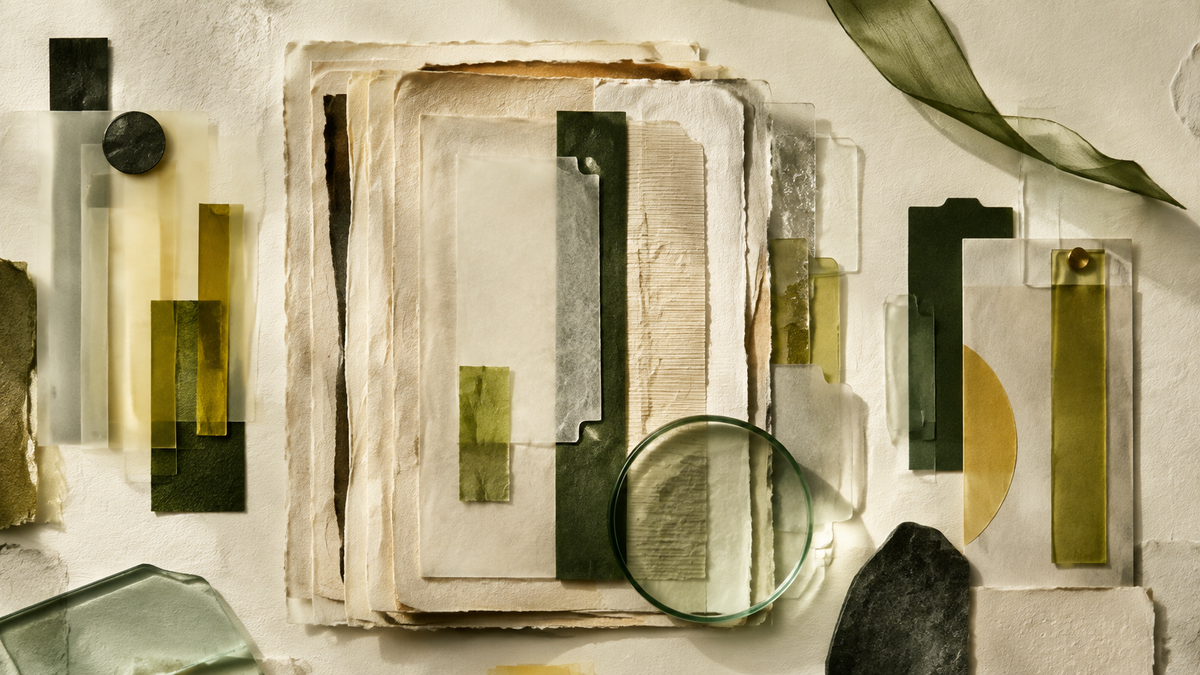 An abstract archive of layered handmade paper, translucent index tabs and a circular glass lens.