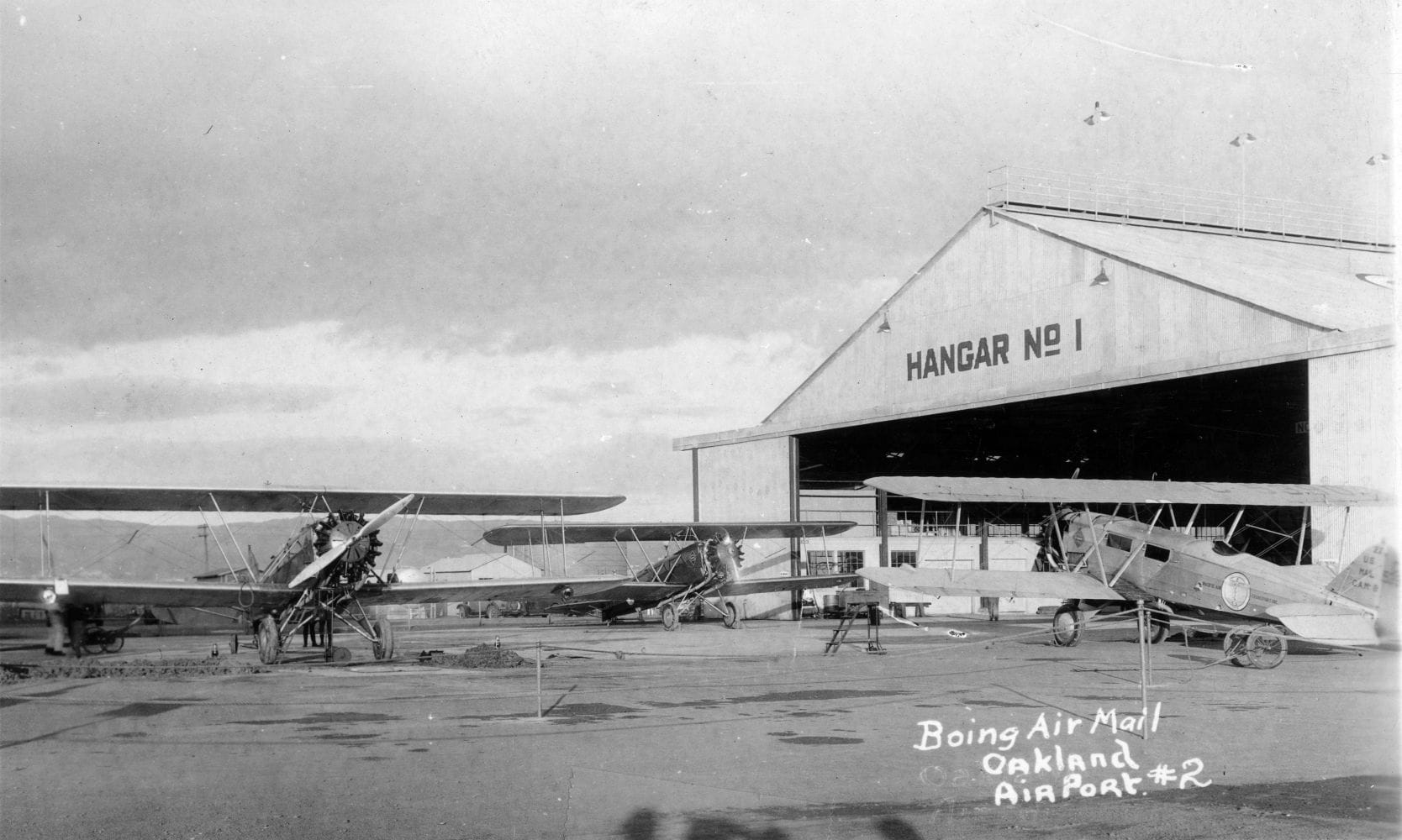 A black-and-white photo showing a few biplanes outside a building reading "HANGAR NO 1."