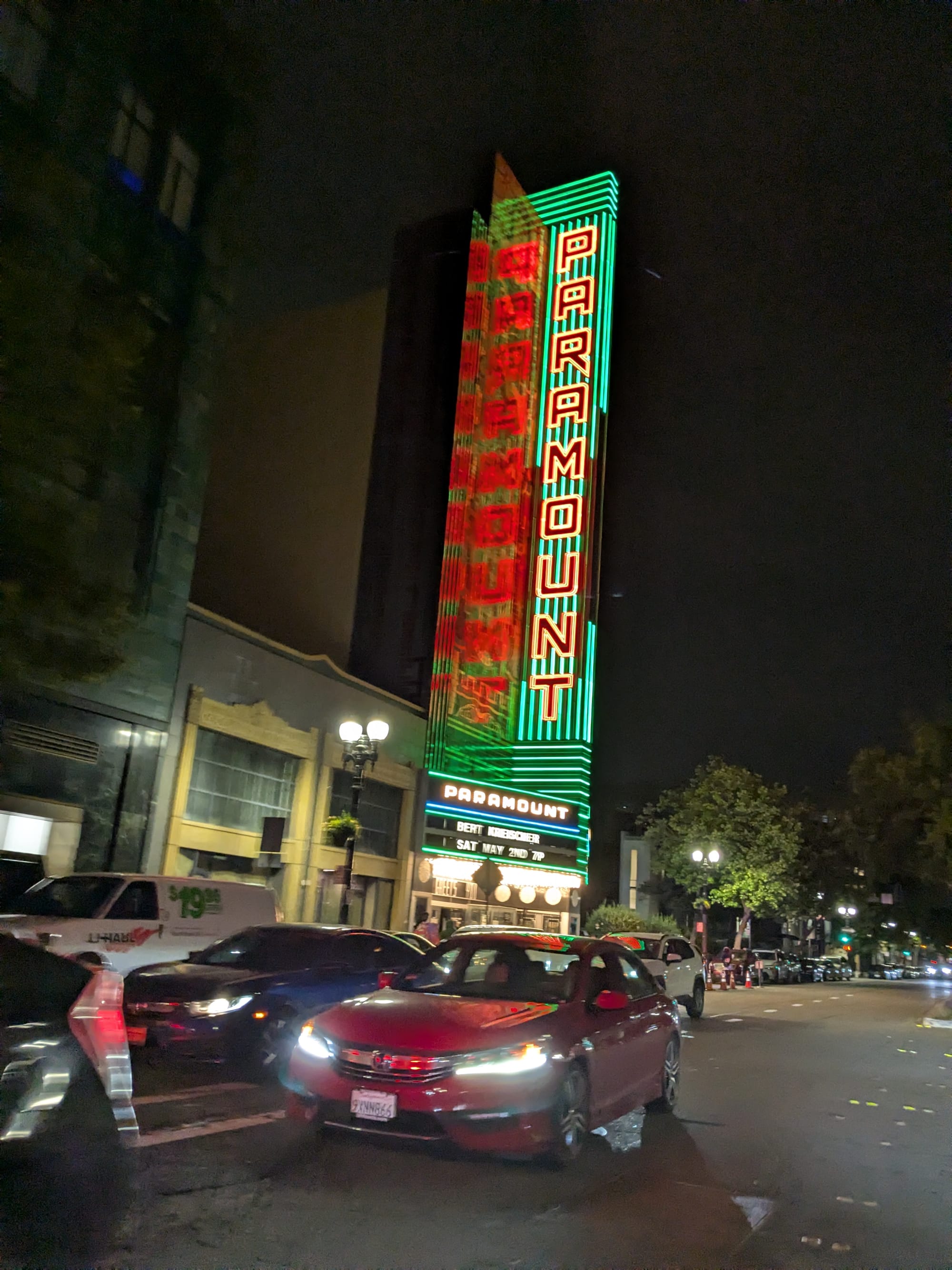 the paramount, lit up at night, cars in foreground