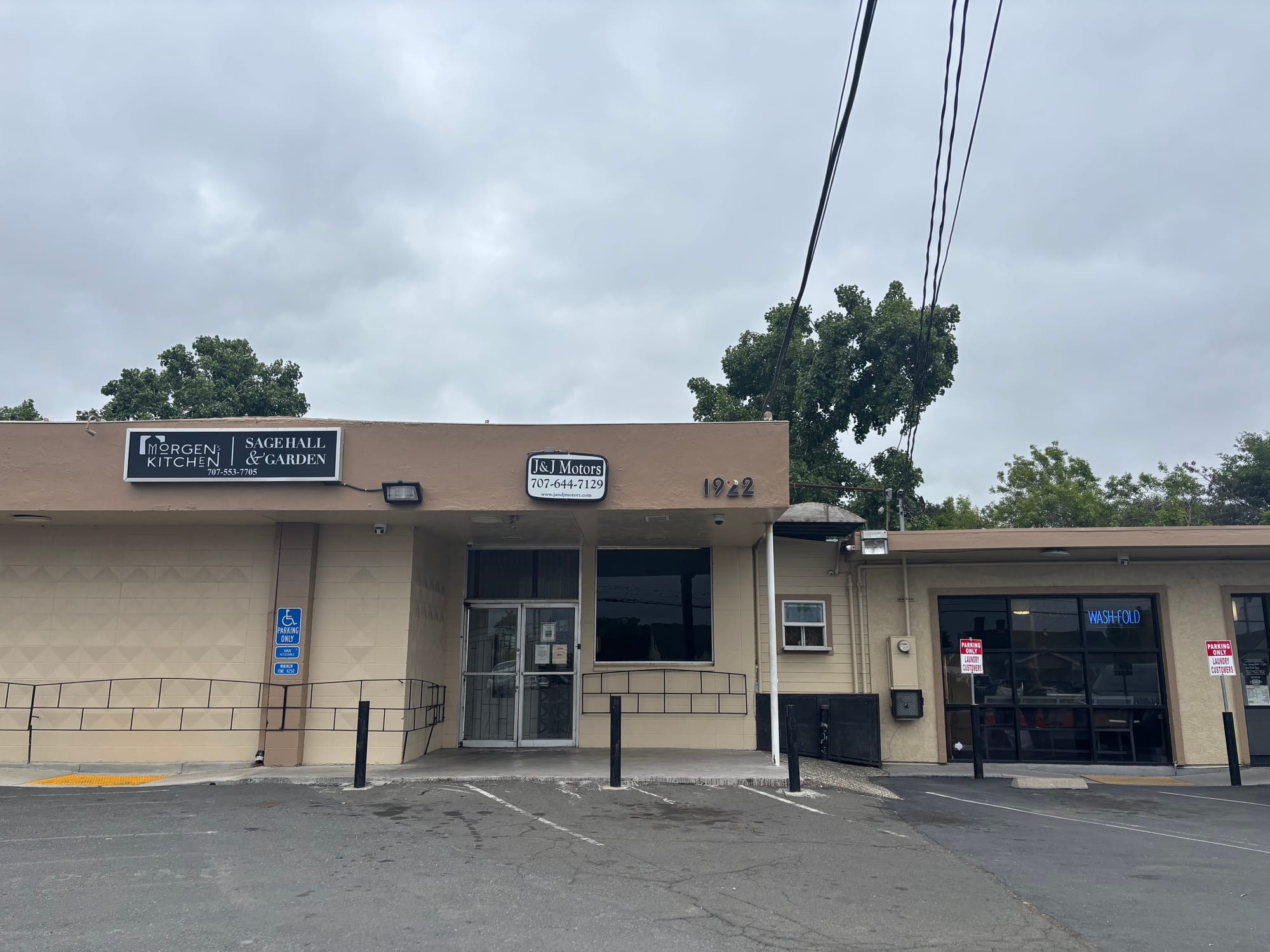 The strip mall in question—beige buildings set against a slate-gray sky, with powerlines overhead. A dreary scene.