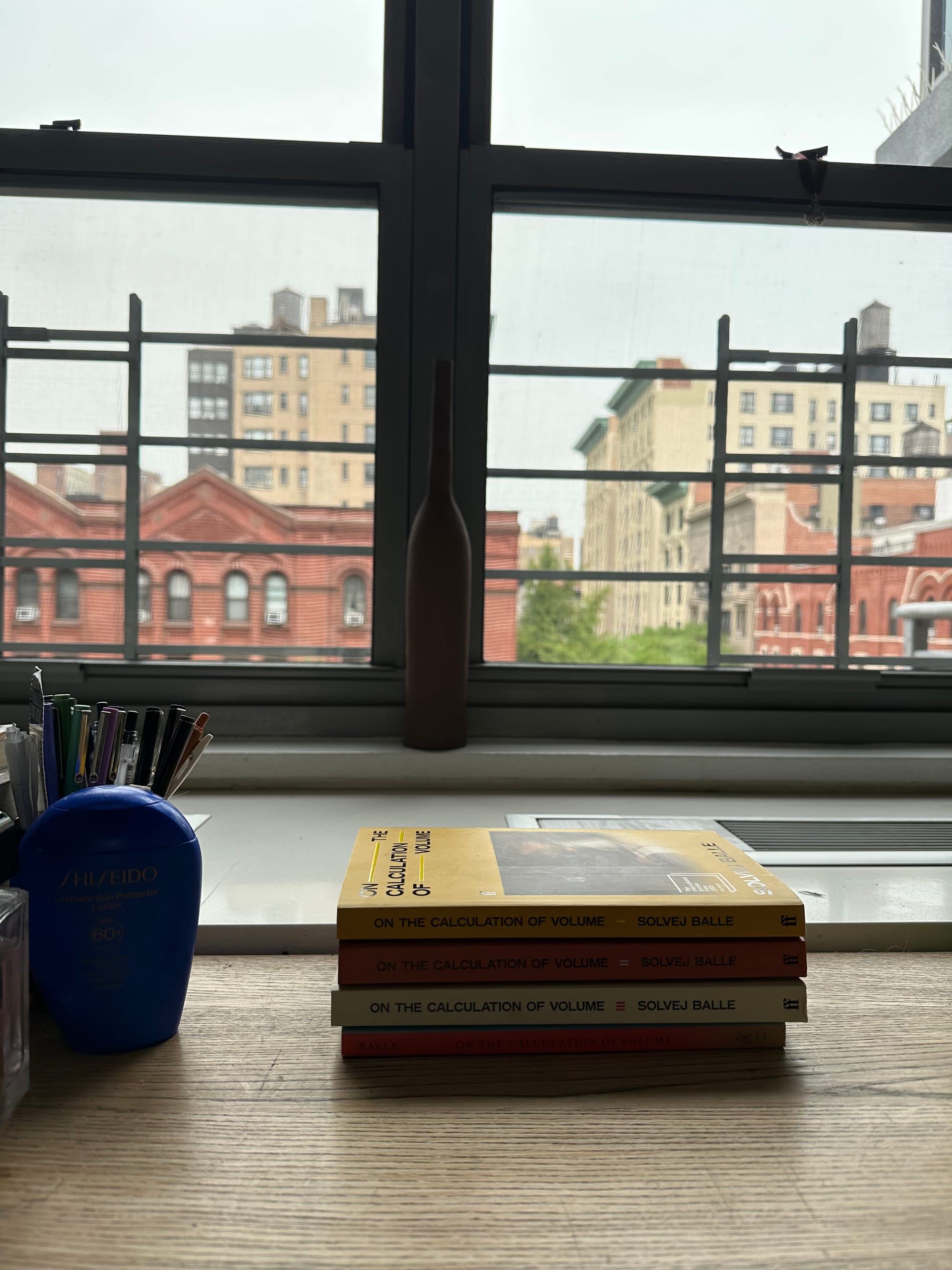four books on a wooden desk, with a view of the city, stacked and brighter now.