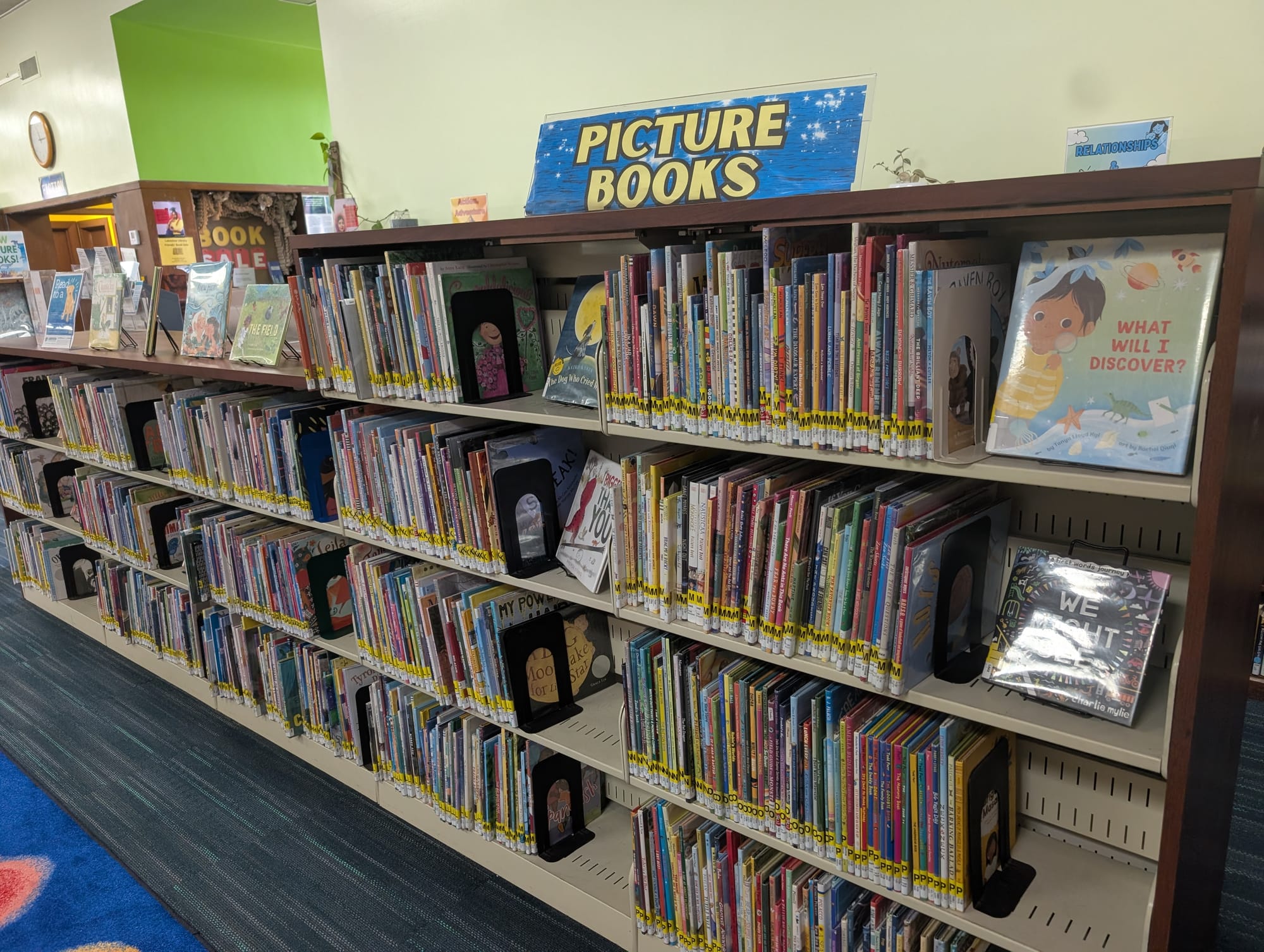 A shelf of colorful and variously sized children's books, with a sign on top reading "PICTURE BOOKS."