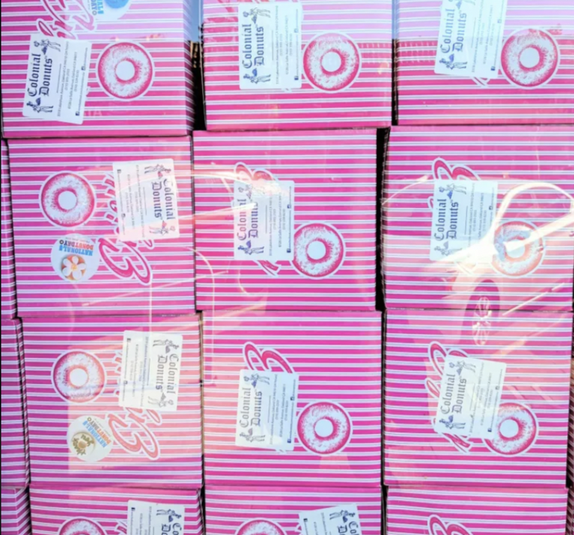 Piled pink Colonial Donuts boxes of (you guessed it)