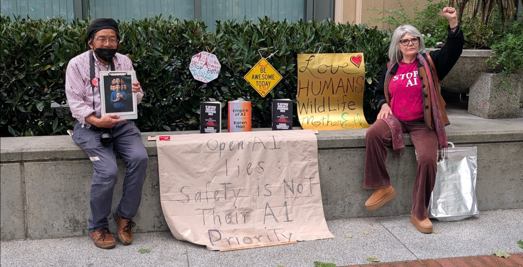 The STOP AI display, books and signs and two protesters.