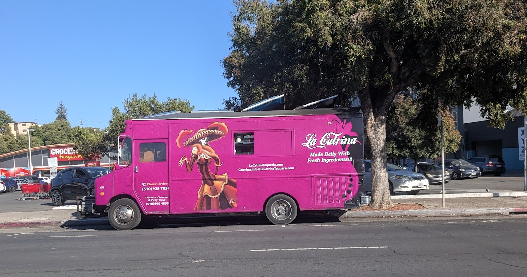 Side of a taco truck with a Día de Muertos style figure.