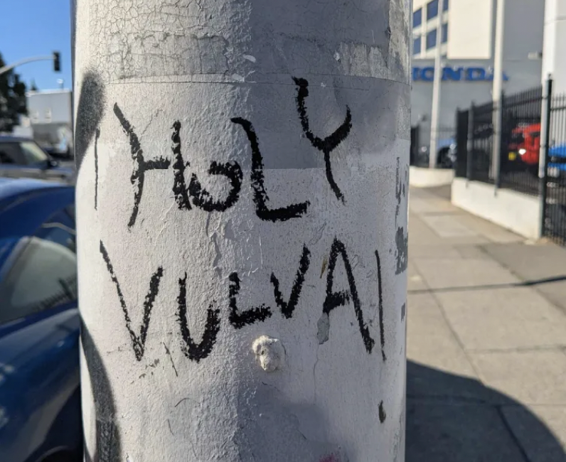 Graffiti on a pole reading "Holy Vulva"