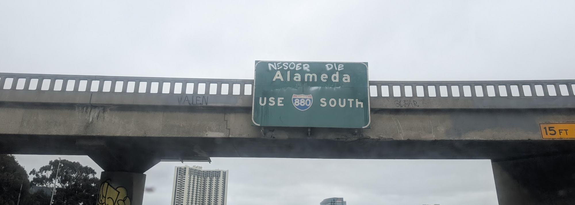 A "Use 880 South" sign that has "Nesoer Die" graffiti.