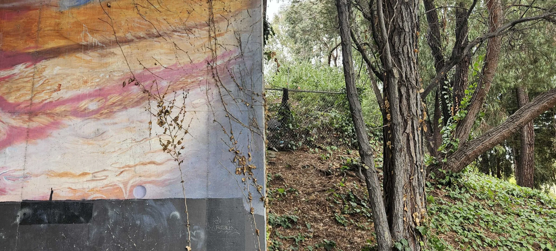 A natural boundary between a wall painted in Jupiter-esque colors and a green hillside.