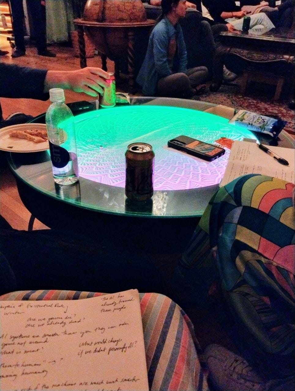 a hand grasping a craft drink, softly, in a photo taken from the vantage point of a person in the room.