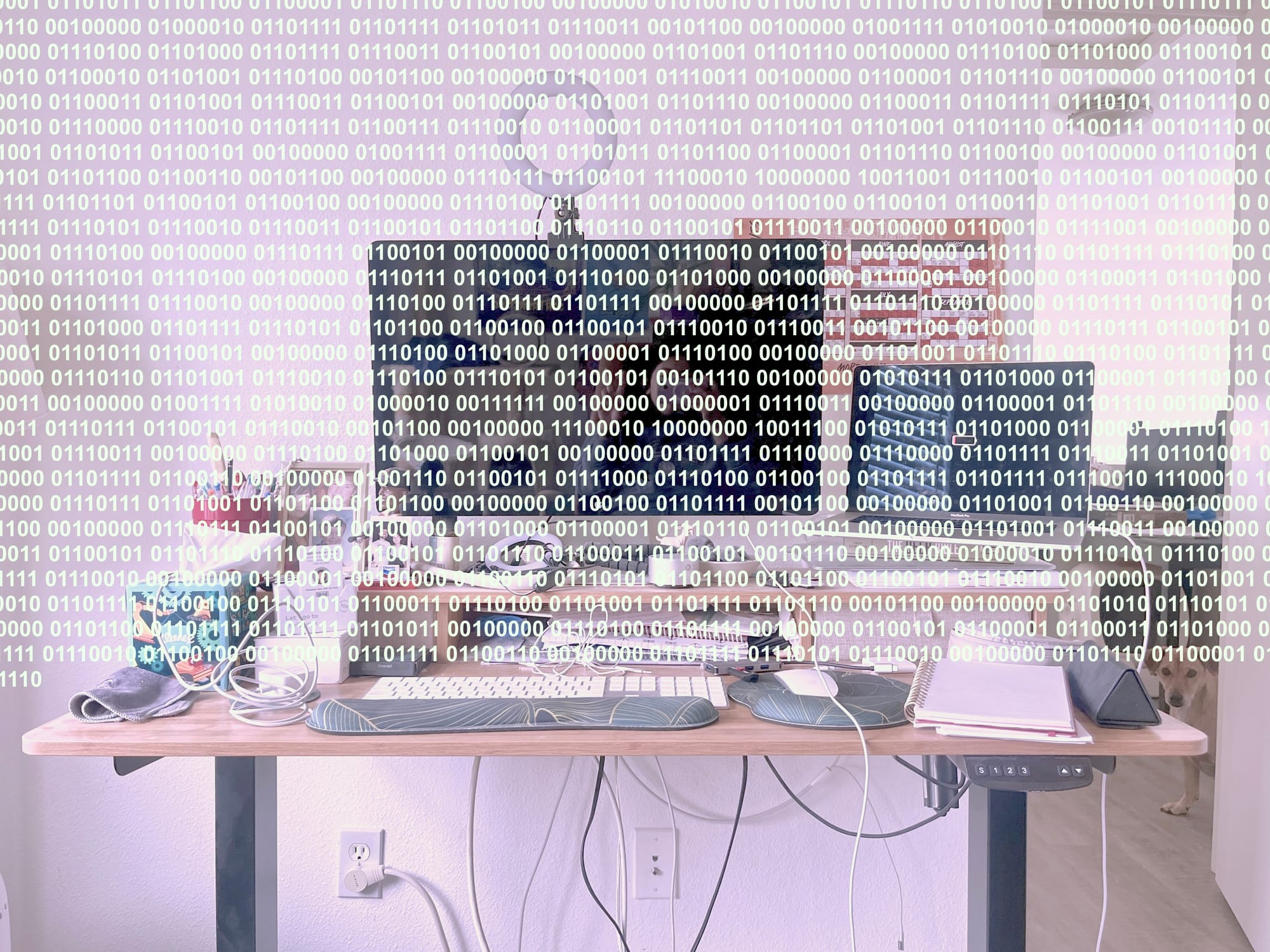 Same desk photo, now with a sickly pinkish hue. Two-thirds of the image is overlaid with binary code.