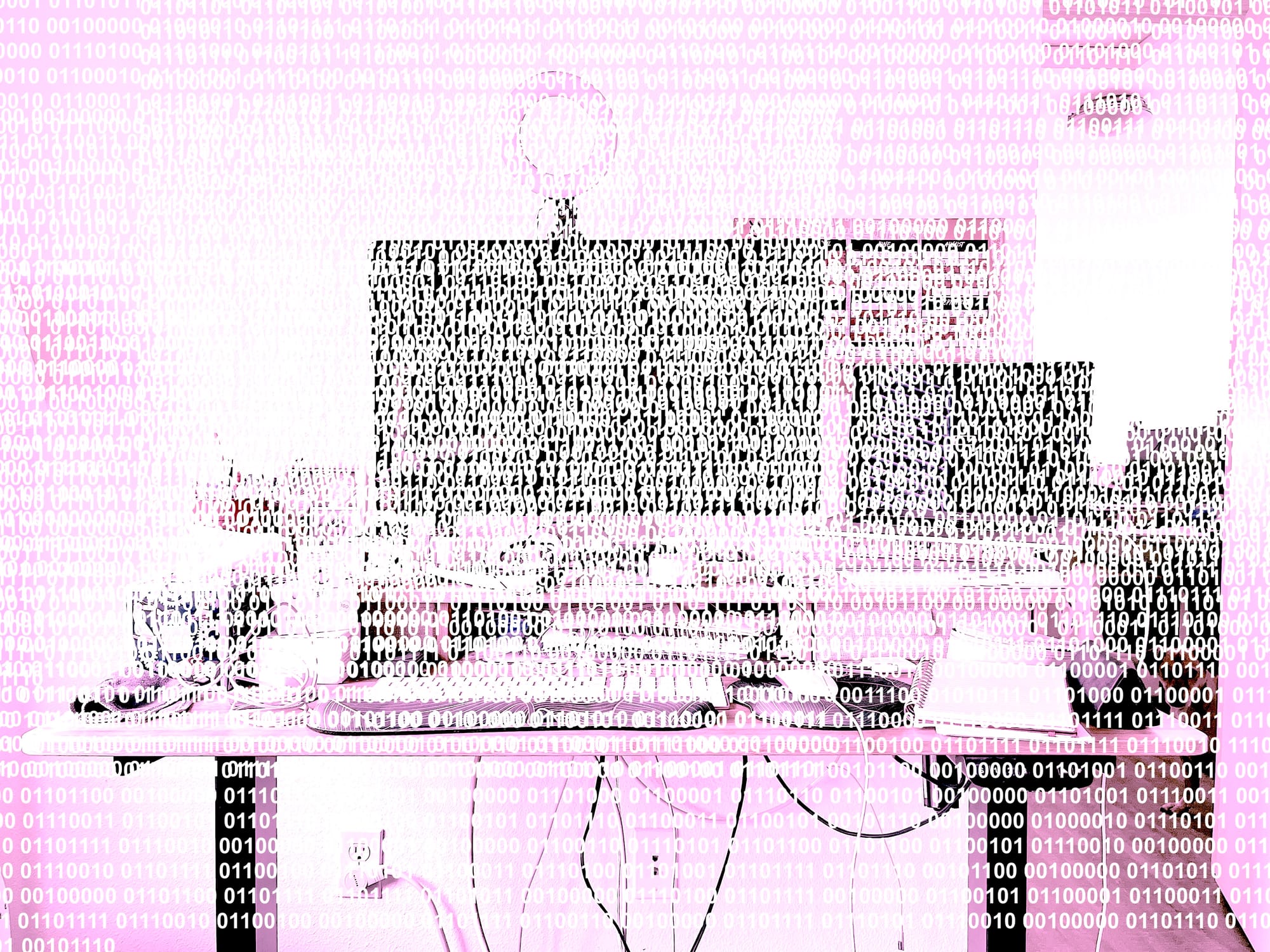 Same desk photo, even more pink and lossy, with the whole image overlaid with binary code.