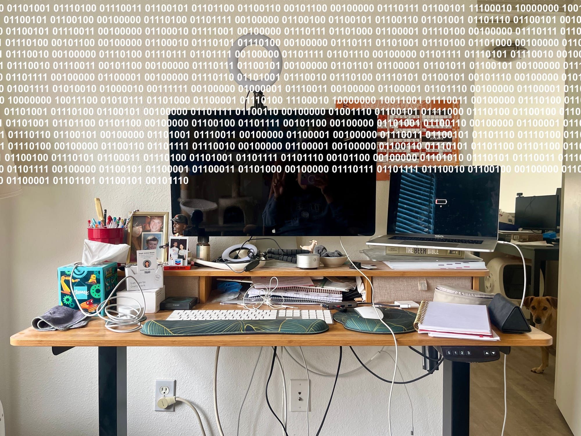Author's cluttered desk, with computers resting on top. The top third of the image is overlaid with binary code.