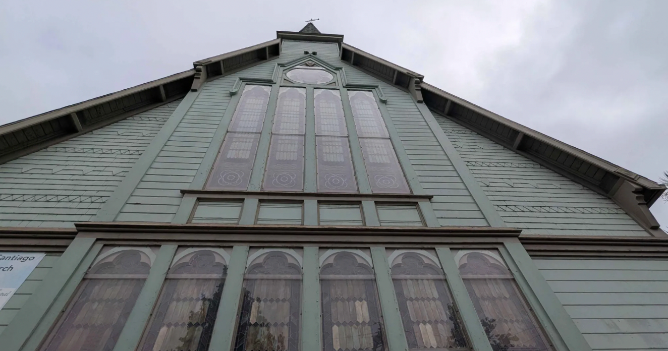 Looking up at a big green church wall.