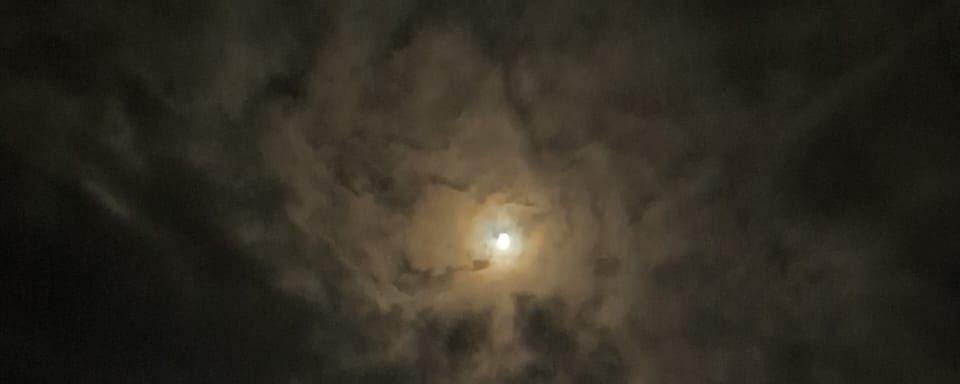 Photo of a cloud-covered moon, with a ghostly penumbra.