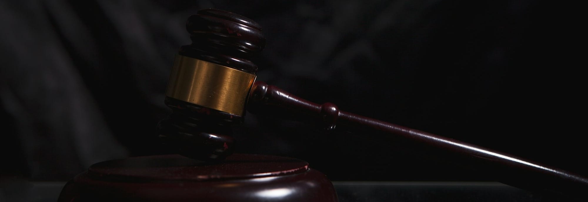 A wooden gavel rests on a dark surface.
