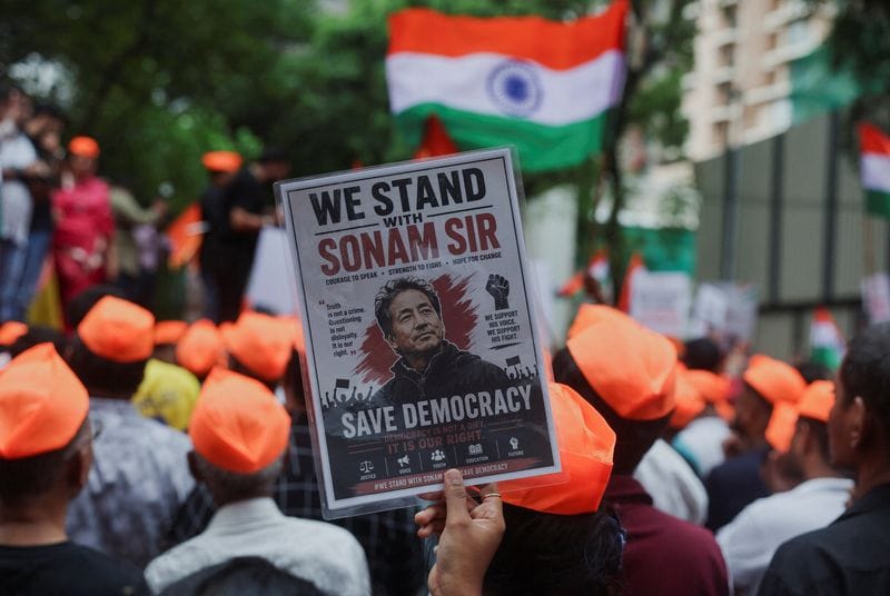 A supporter of the Cockroach Janta Party (CJP) holds a poster of Sonam Wangchuk after authorities moved him to a hospital during his hunger strike, during a protest demanding the resignation