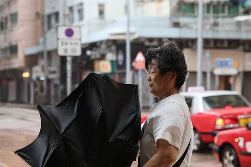 A pedestrian holds an inverted umbrella against strong winds during heavy rain from Typhoon Noul, in Hong Kong