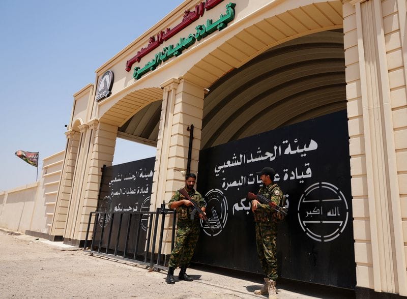 Members of Iraq's Popular Mobilization Forces (PMF) stand guard outside the Basra Operations Command headquarters, following airstrikes that the PMF said were carried out by U.S. and Saudi