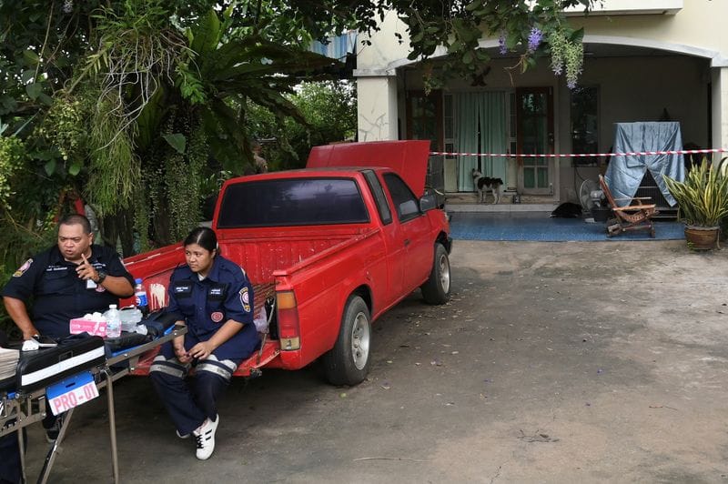 Emergency personnel sit outside the house where a Thai teenager fatally shot his grandparents, on the outskirts of Bangkok