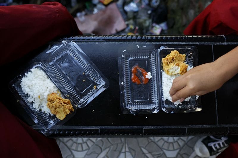Students eat from plastic containers at a school in the fishing village of Torosiaje