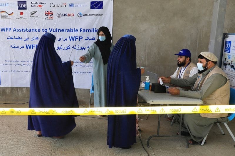 FILE PHOTO: Afghan women arrive to receive assistance from a World Food Program distribution centre in Kabul