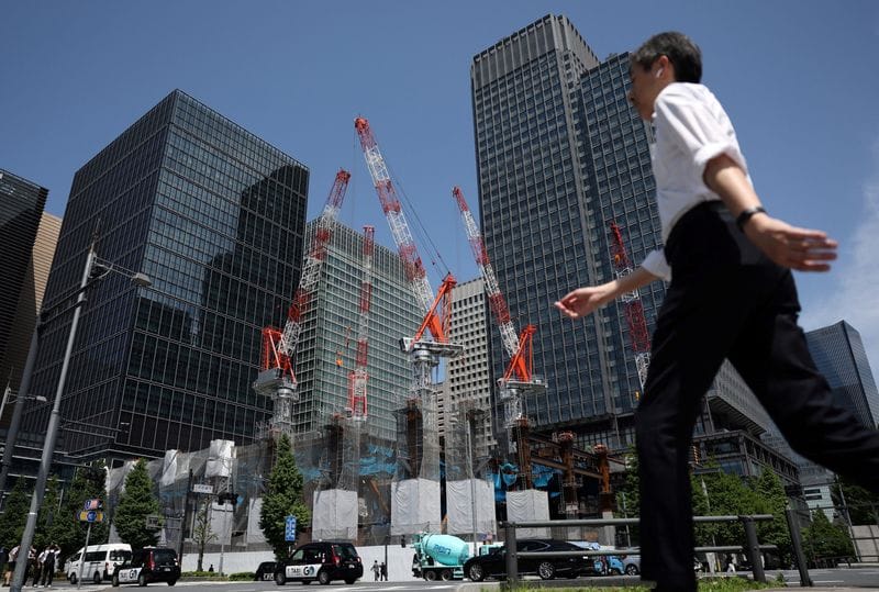 A man walks past on the street near a construction site in Tokyo