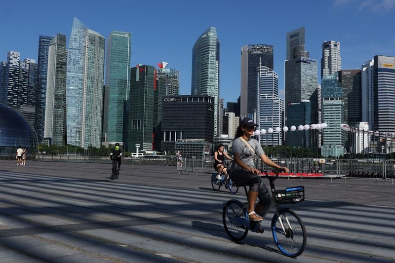 People ride bikes past the skyline of the central business district in Singapore