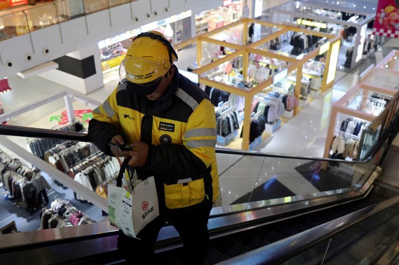 FILE PHOTO: Delivery worker picks up a food order at a shopping mall in Beijing