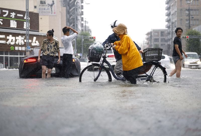 People move along a road flooded by heavy rain in Nagoya