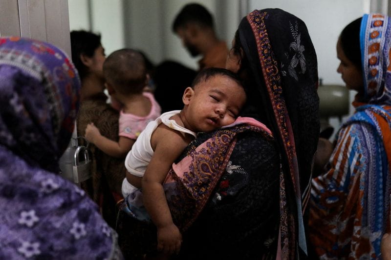 A woman carries a child, who suffers from measles, for treatment at a hospital in Dhaka