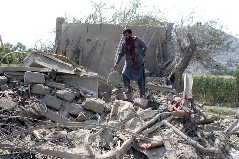 A man retrieves belongings from the debris of a house that was damaged in what the Taliban said was a Pakistani airstrike in Kunar province