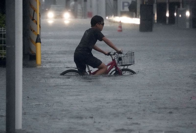 A boy cycles through a flooded street as Typhoon Dujuan brings heavy rain, in Ichikawa