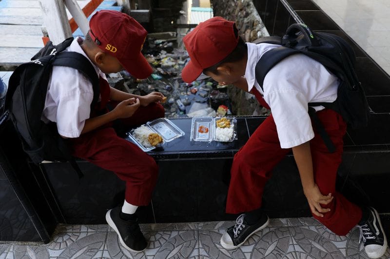 Students eat from plastic containers at a school in the fishing village of Torosiaje